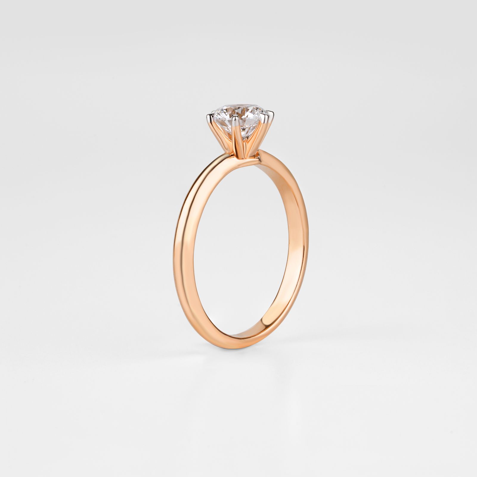 A gold-toned solitaire engagement ring on a light studio background
