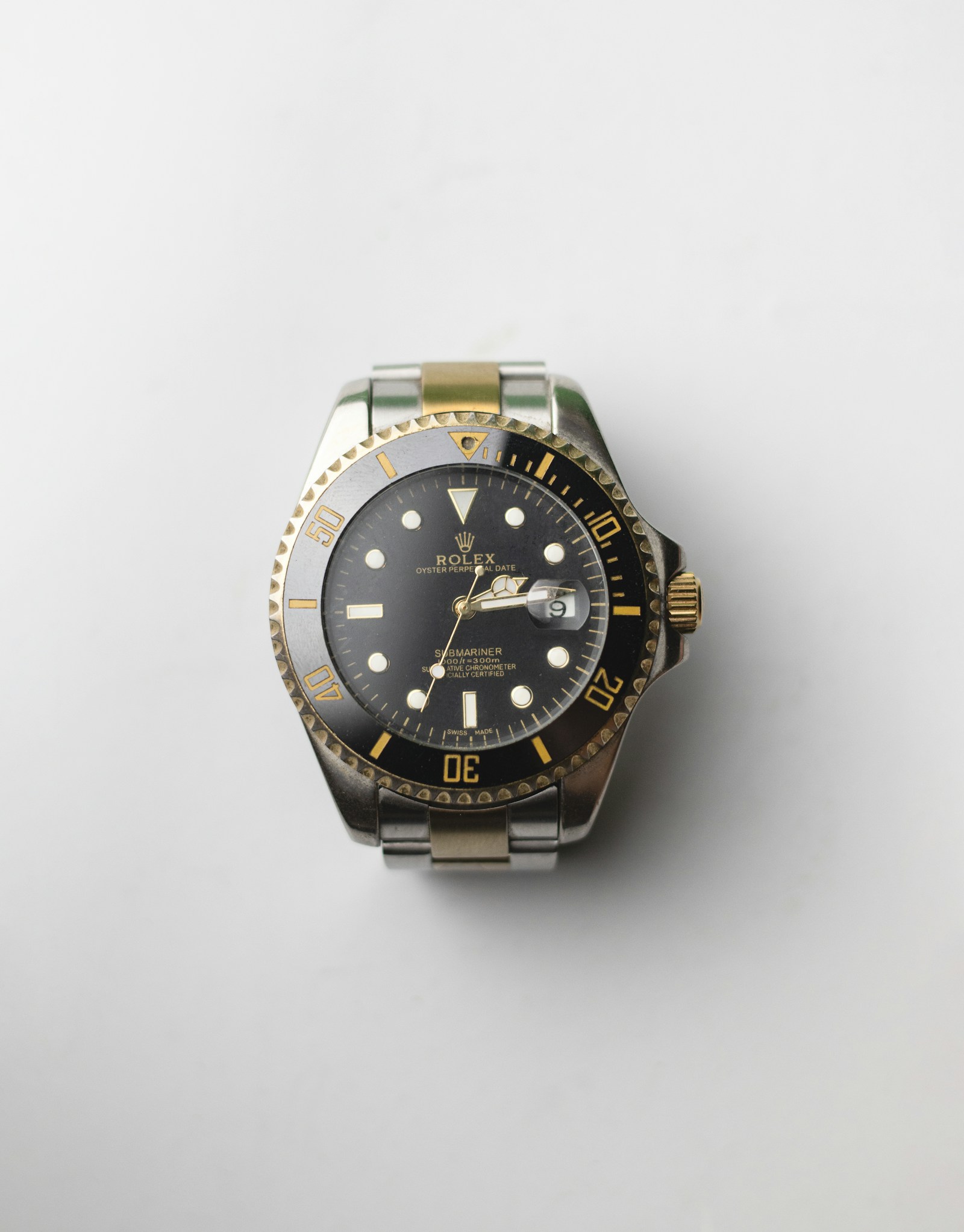 A two-tone Rolex Submariner on a plain light studio surface